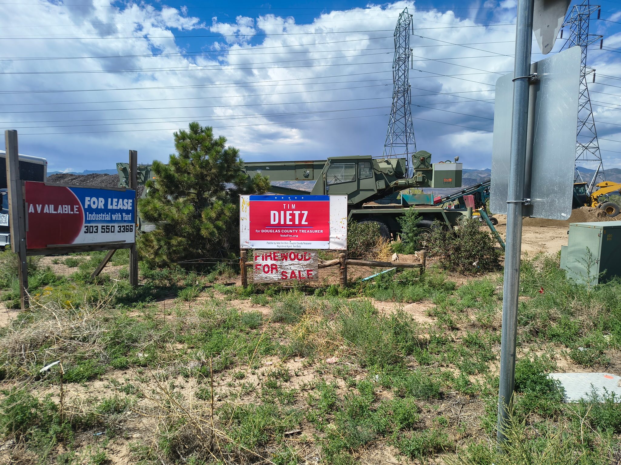A Tim Dietz for Douglas County Treasurer campaign sign on Santa Fe Drive in Highlands Ranch at Silver Crown Landscaping near Murdoch's, next to a For Lease sign and a hand-painted Firewood For Sale board
